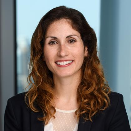photo of woman wearing white top and black blazer with curly orange hair smiling