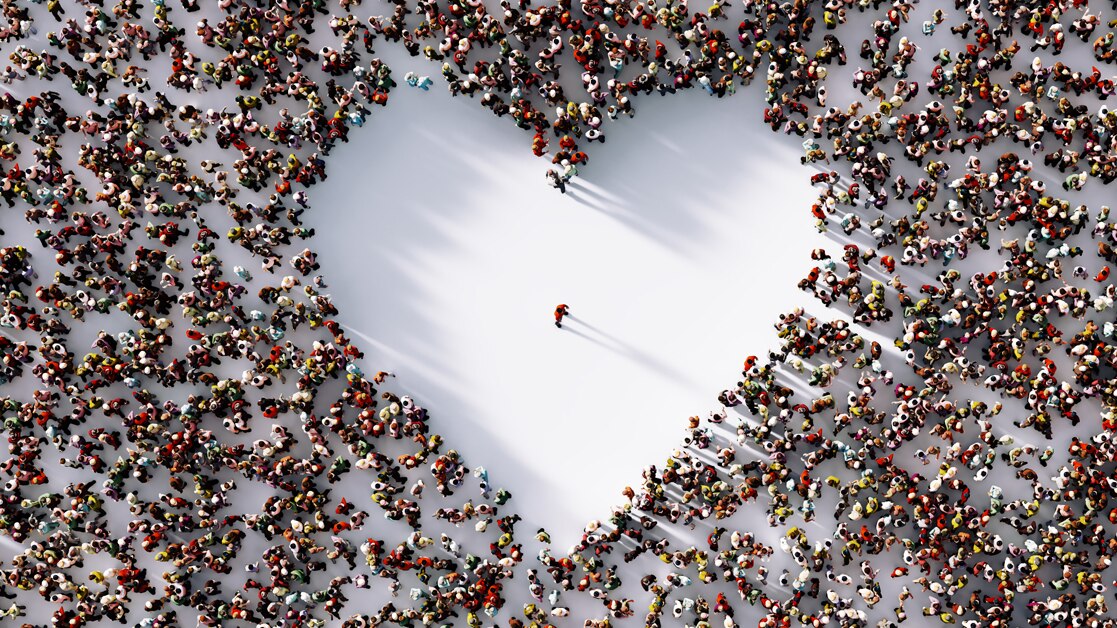 Lone man standing in a white heart shaped void formed by a surrounding crowd